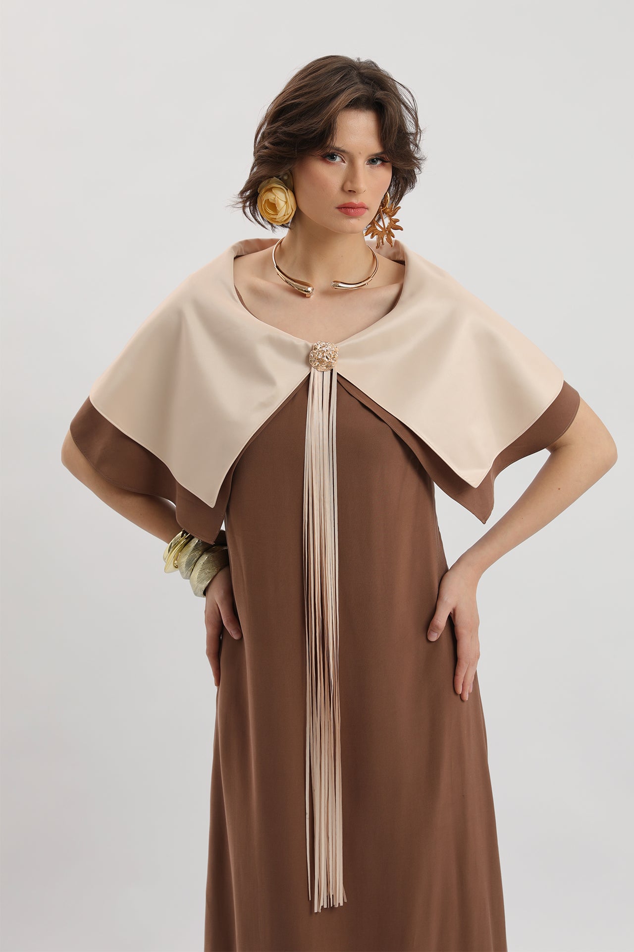 Coffee-colored midi dress with cape, brooch and tassel details.